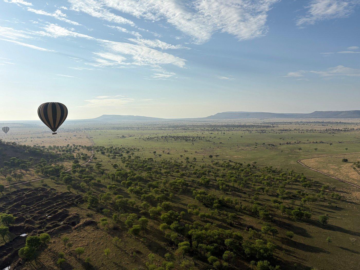 Hot air balloon floating above the Tanzanian savannah with a wide landscape view