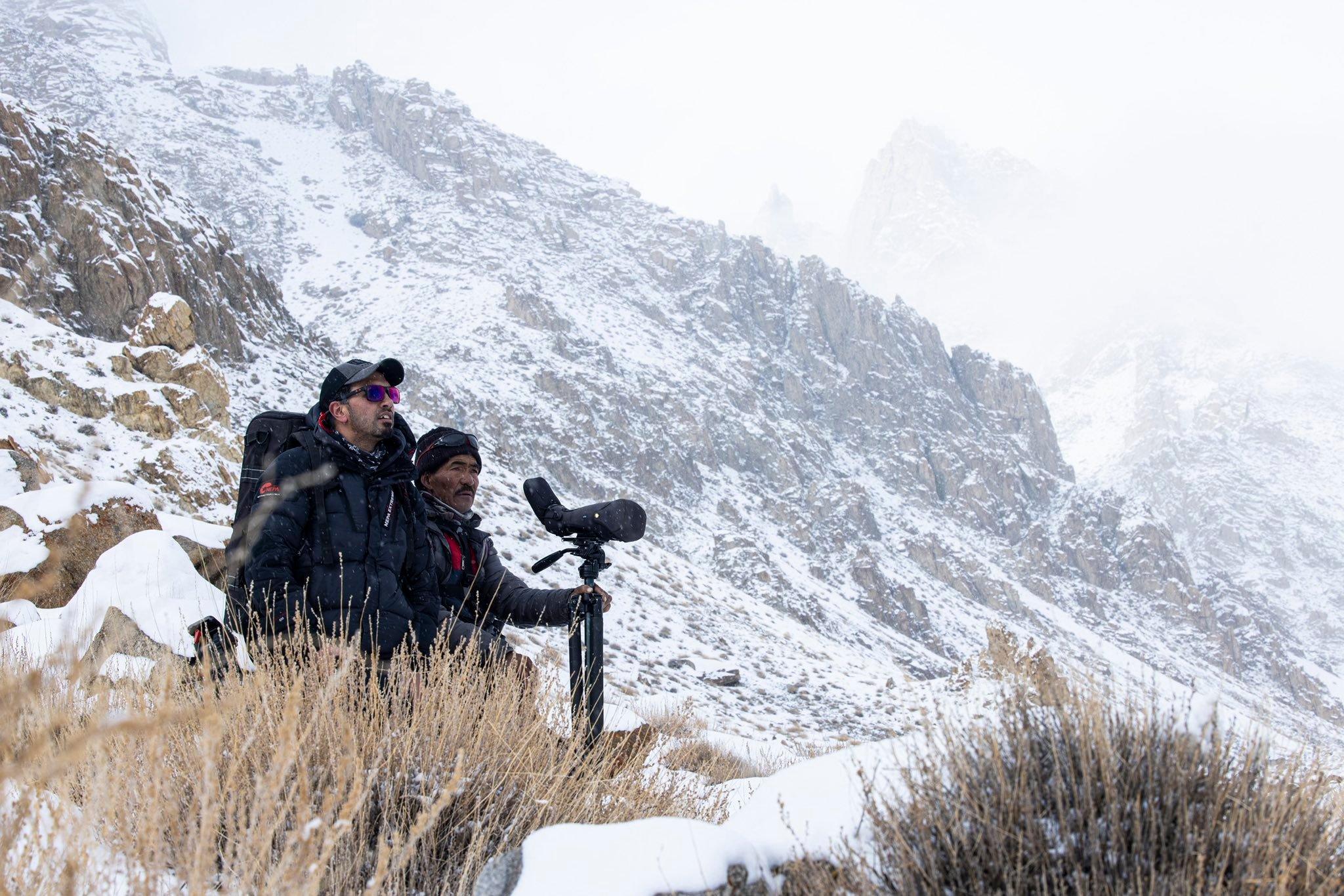 Snow leopard expedition team scanning mountain slopes with optics